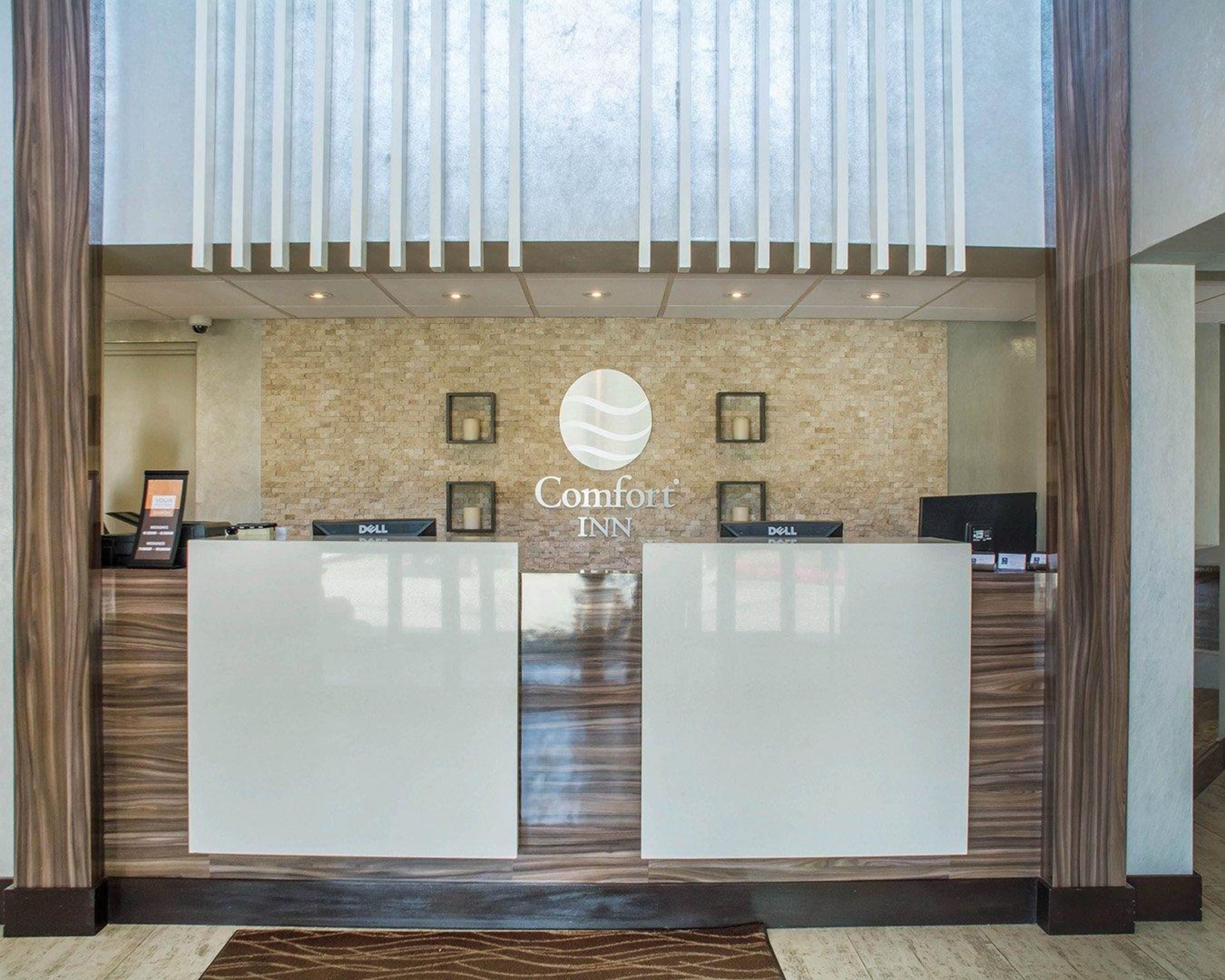 Una mesa de recepción con un letrero que dice "Comfort INN" y dos estaciones de trabajo con la marca Dell.