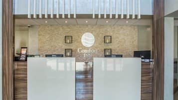 Una mesa de recepción con un letrero que dice "Comfort INN" y dos estaciones de trabajo con la marca Dell.