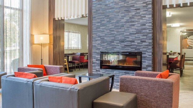 A modern living room with a fireplace, leather sofas, and a dining area in the background. - Comfort Inn Burlington (Burlington)
