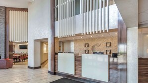A modern reception area with a reception desk, a seating area with a sofa, and a dining area in the background. - Comfort Inn Burlington (Burlington)