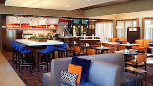 Un hall d’hôtel comprenant un bar, des espaces aménagés avec des sièges et un comptoir.