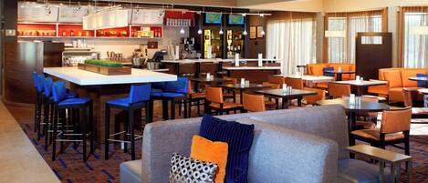 A hotel lobby with a bar area, seating arrangements, and a counter.