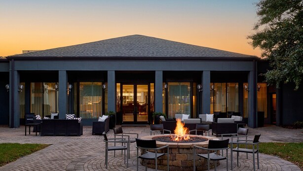 A building with a fire pit in the center, surrounded by outdoor seating. - Courtyard Fairfax Fair Oaks (Fairfax)