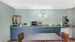 Un restaurante pequeño y compacto con mostrador, microondas y un reloj en la pared.