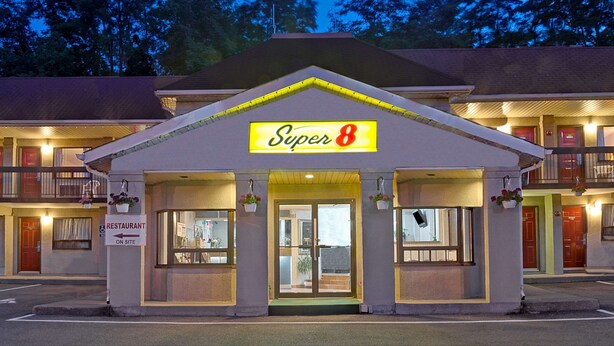 Un motel con un letrero de 'Super 8', un letrero de restaurante y un letrero de 'No Estacionamiento'.