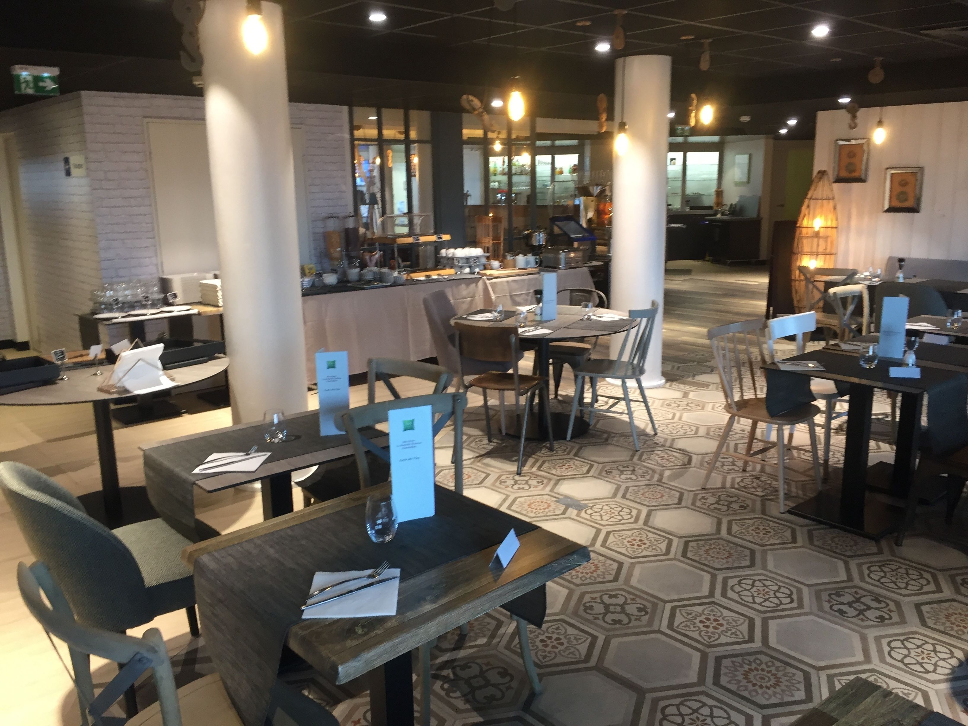 A restaurant with hexagonal patterned flooring, tables with menus, and chairs.