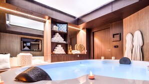 A modern spa room with a large bathtub, wooden shelves with towels and decorative items, and a wooden wall with a framed picture. - Ibis Styles La Rochelle Thalasso Châtelaillon (Chatelaillon-Plage)