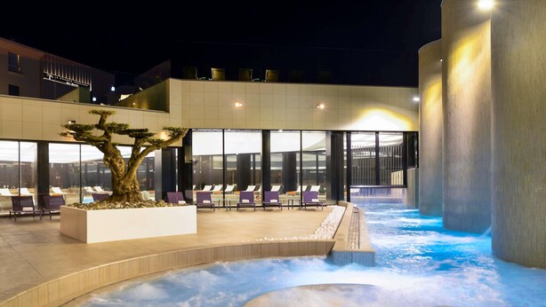 A spa area with a hot tub, lounge chairs, and a large tree. - Ibis Styles La Rochelle Thalasso Châtelaillon (Chatelaillon-Plage)