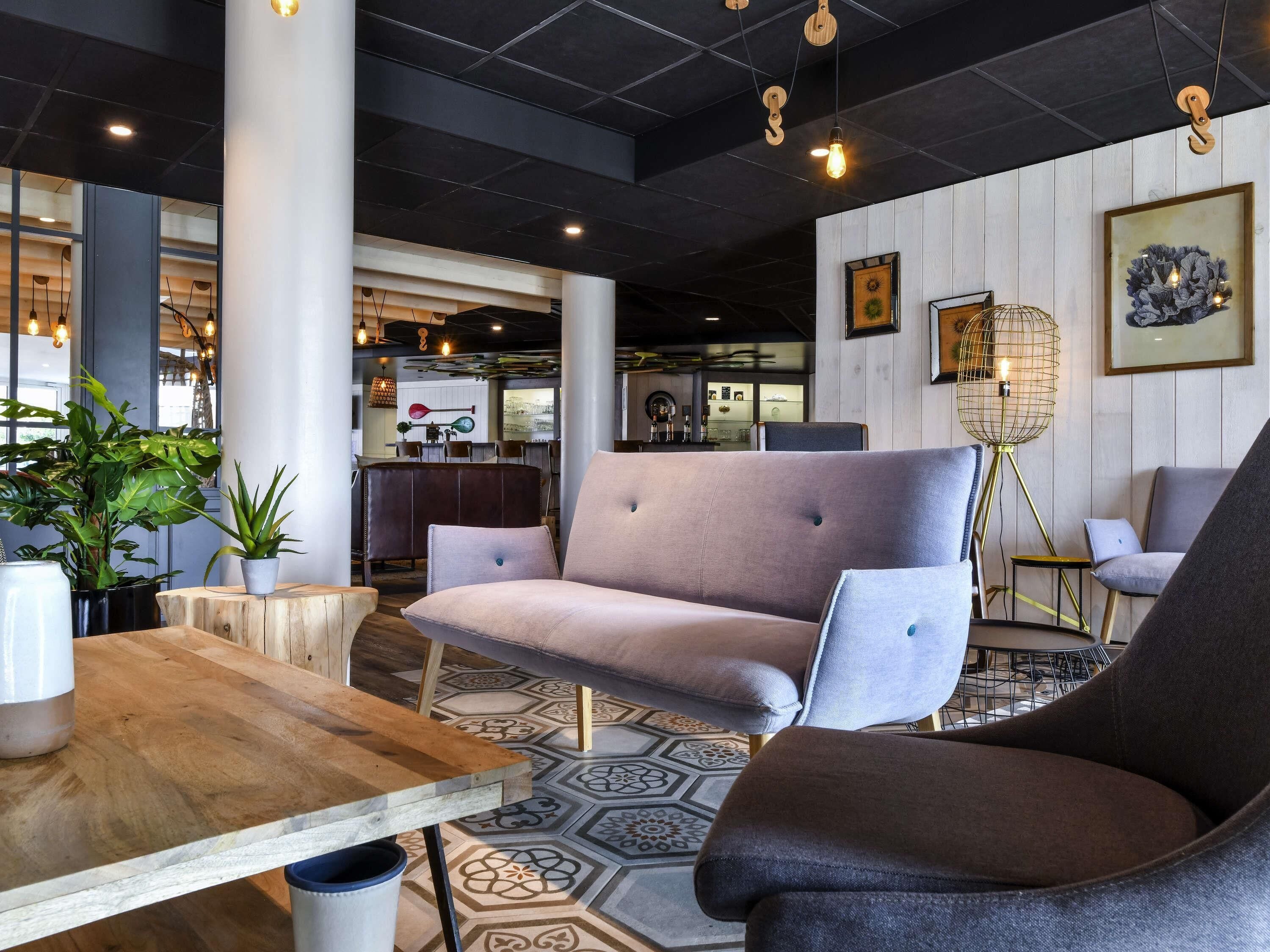 Un interior moderno con un sofá, sillas, una mesa de madera y un suelo estampado.