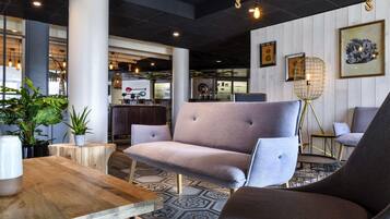 Un interior moderno con un sofá, sillas, una mesa de madera y un suelo estampado.