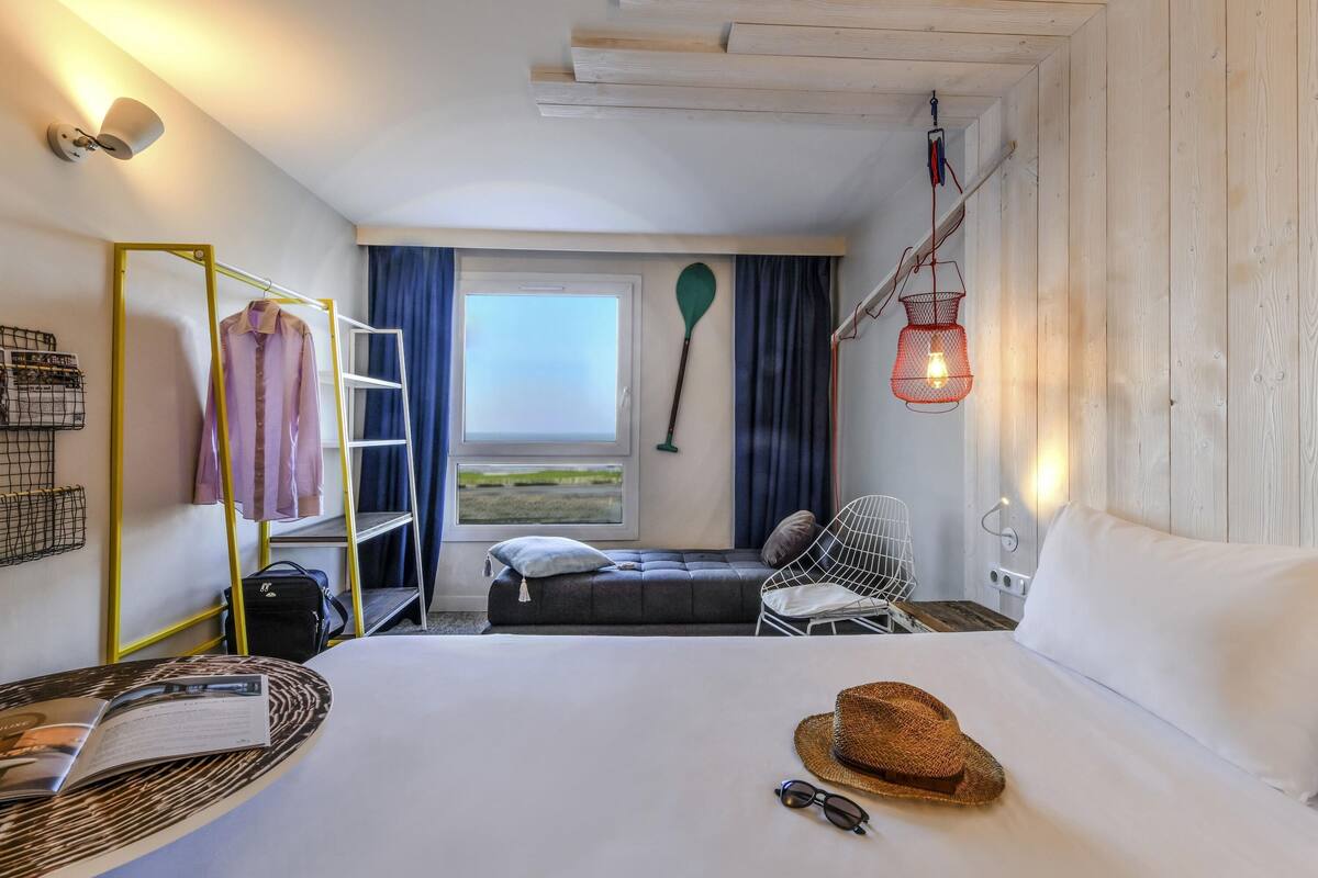 A room with a bed, a desk, a chair, a window, and a hanging light fixture.