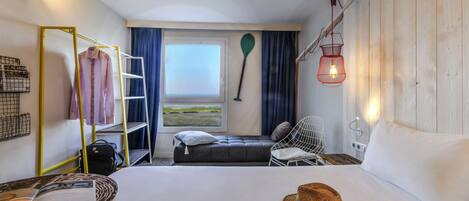 A room with a bed, a desk, a chair, a window, and a hanging light fixture.