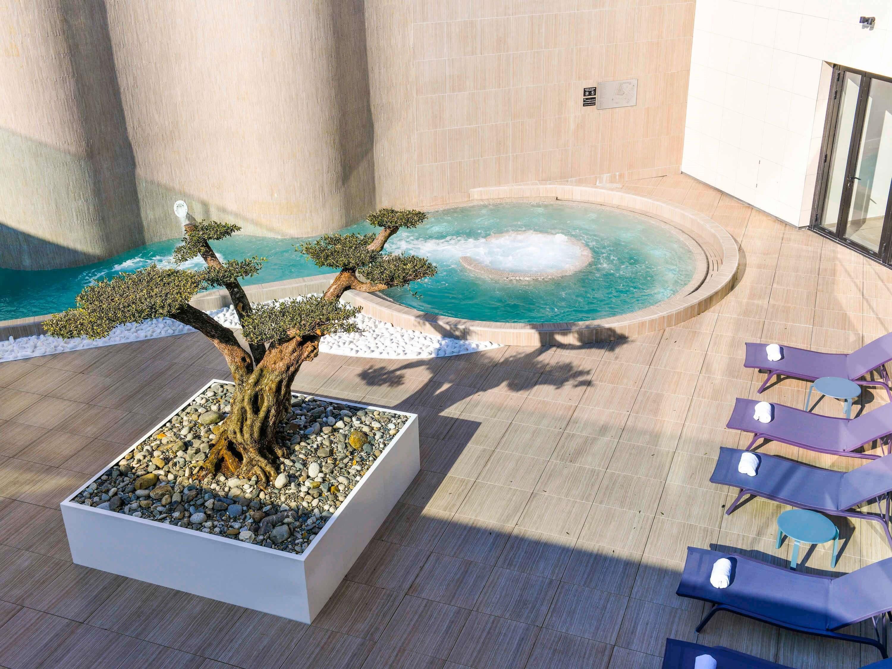 A spa area with a hot tub, lounge chairs, and a bonsai tree.