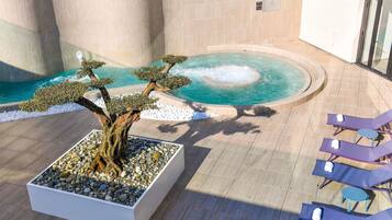 A spa area with a hot tub, lounge chairs, and a bonsai tree.