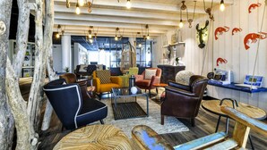 A modern lounge area with wooden furniture, hanging lights, and a visible seafood-themed wall decoration. - Ibis Styles La Rochelle Thalasso Châtelaillon (Chatelaillon-Plage)