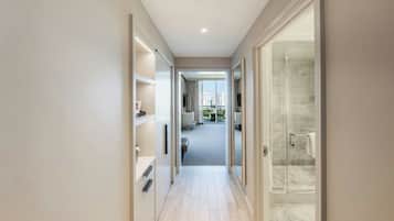 Un pasillo que conduce a un baño con mampara de vidrio y vistas a la ciudad.