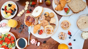 A breakfast spread with various pastries, fruits, and beverages on a wooden table. - JW Marriott Turnberry Resort & Spa (Aventura)
