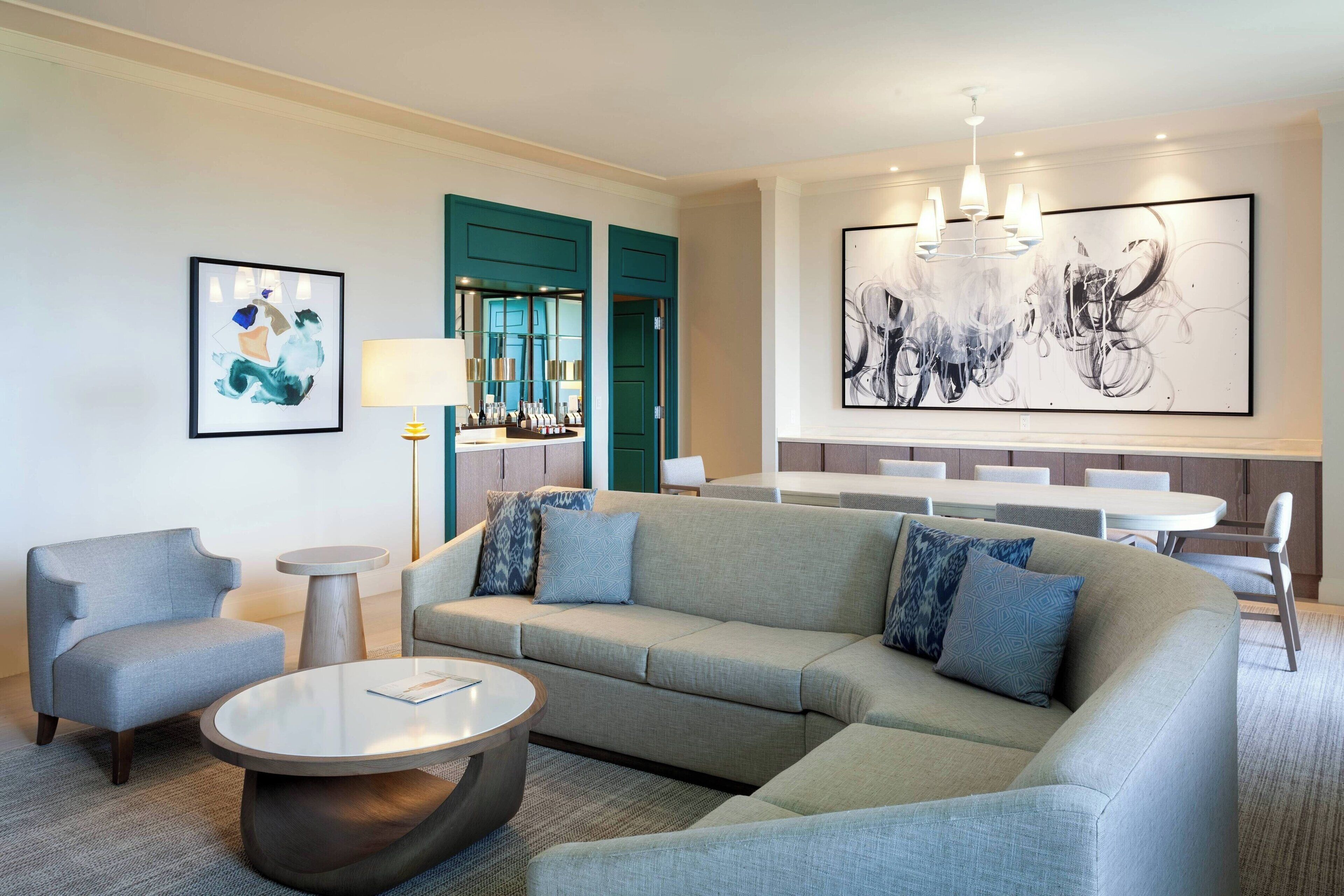 A modern living room with a sectional sofa, a round coffee table, and a dining area with a white table and chairs.
