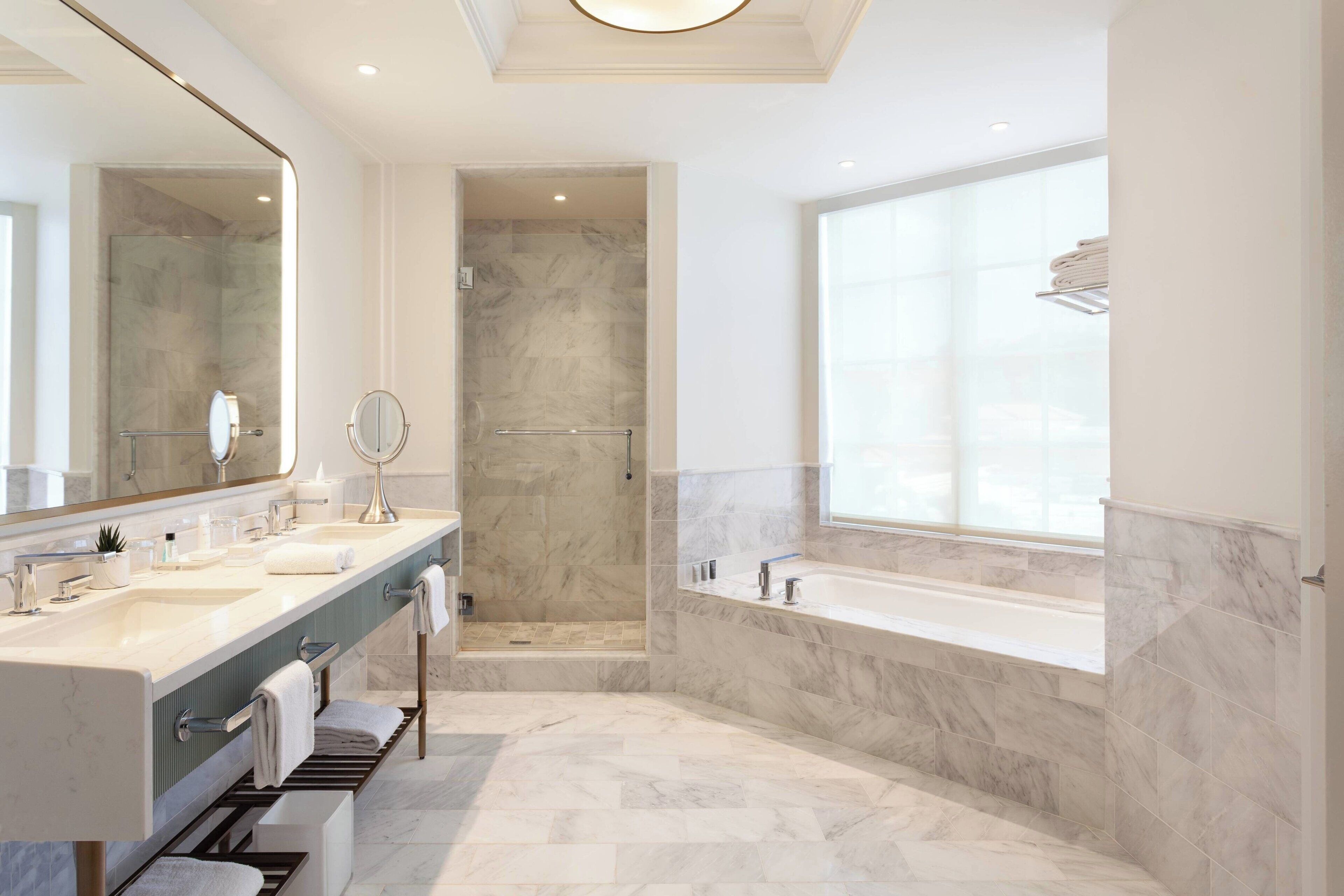 Une salle de bain moderne avec un meuble-lavabo à deux vasques, un grand miroir, une douche à l’italienne et une baignoire.