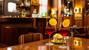 Dos vasos de martini con rodajas de naranja sobre una barra.