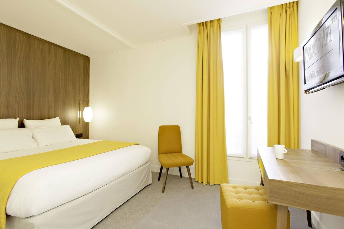 Une chambre d’hôtel avec un lit, une chaise, une table et un téléviseur.