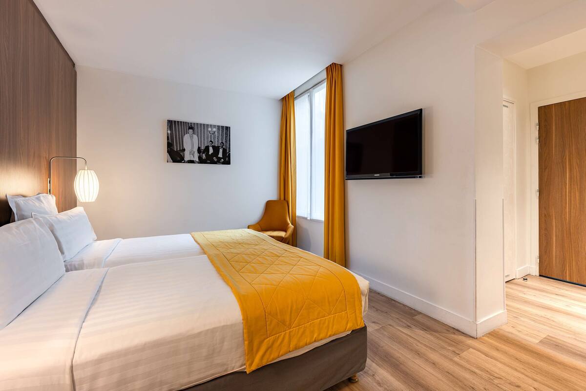 Une chambre d’hôtel avec un lit, une télévision, une chaise et un tableau au mur.
