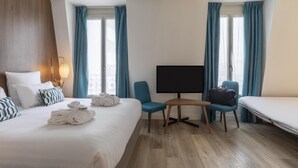 Et hotelværelse med seng, skrivebord, fjernsyn og stol.