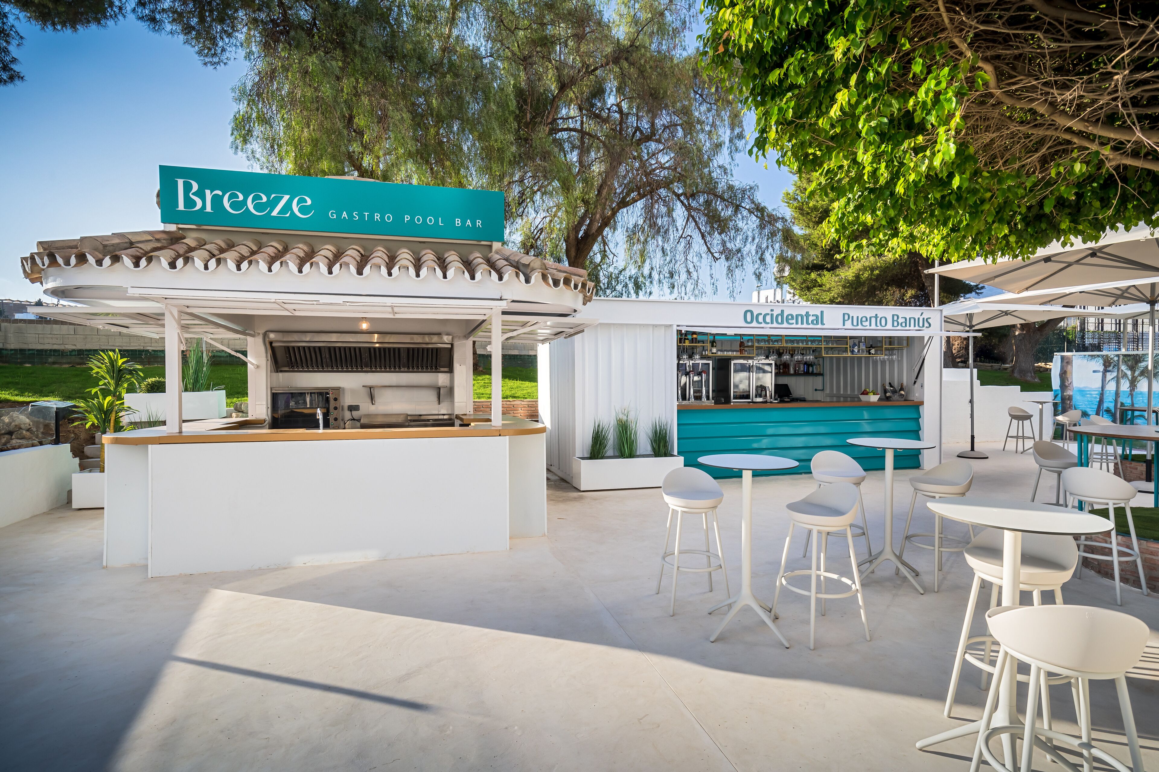 Eine Außenbar mit einer Beschilderung mit dem Aufdruck "Breeze Gastro Pool Bar", weißen Barhocker und einem Billardtisch.