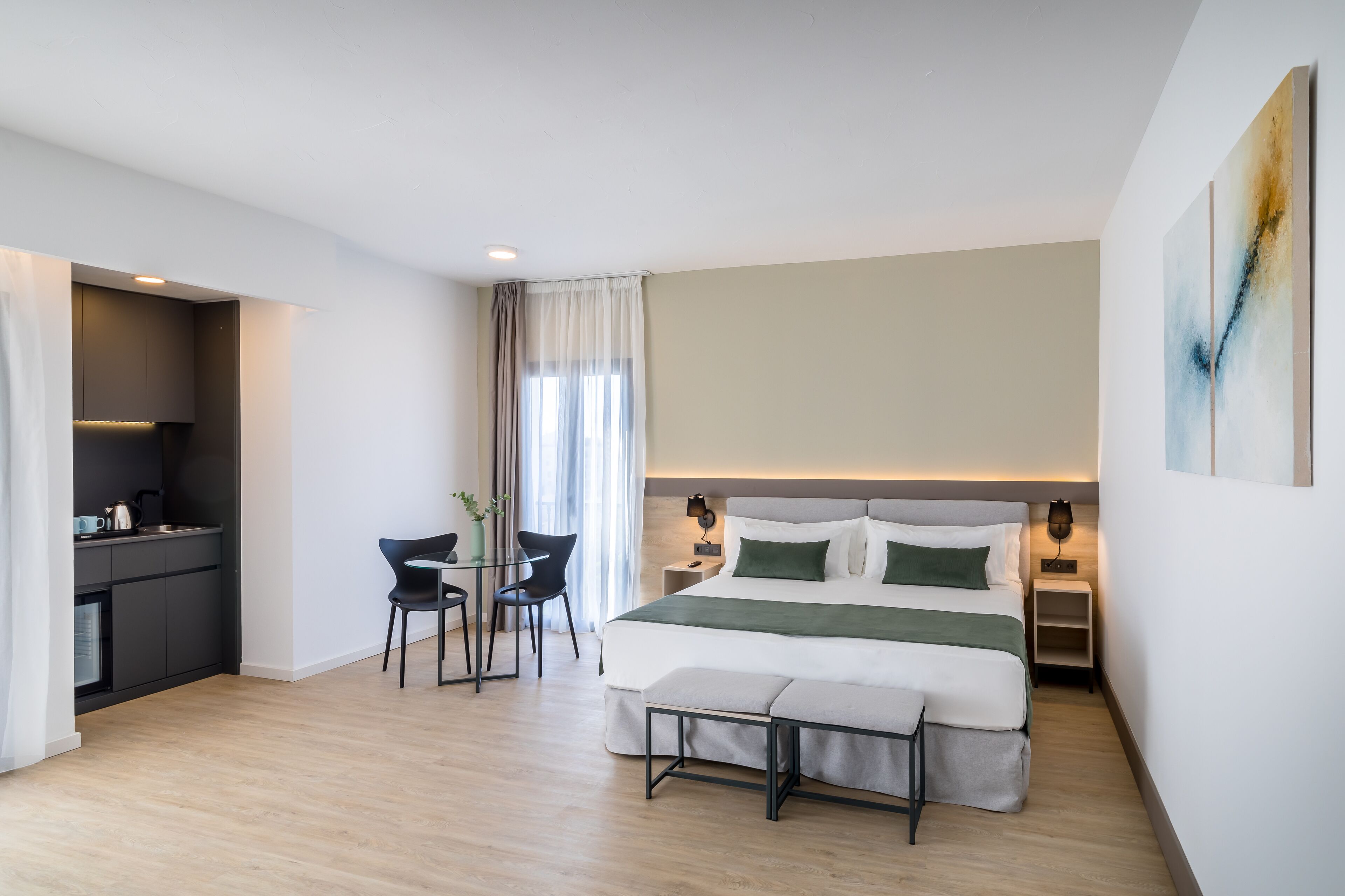 Ett modernt hotellrum med en säng, sängbord, ett litet skrivbord och en stol.