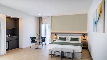 Ett modernt hotellrum med en säng, sängbord, ett litet skrivbord och en stol.