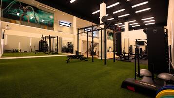 Ein Fitnessstudio mit Trainingsgeräten, Kunstrasenteppich und einer großen Wandmalerei.