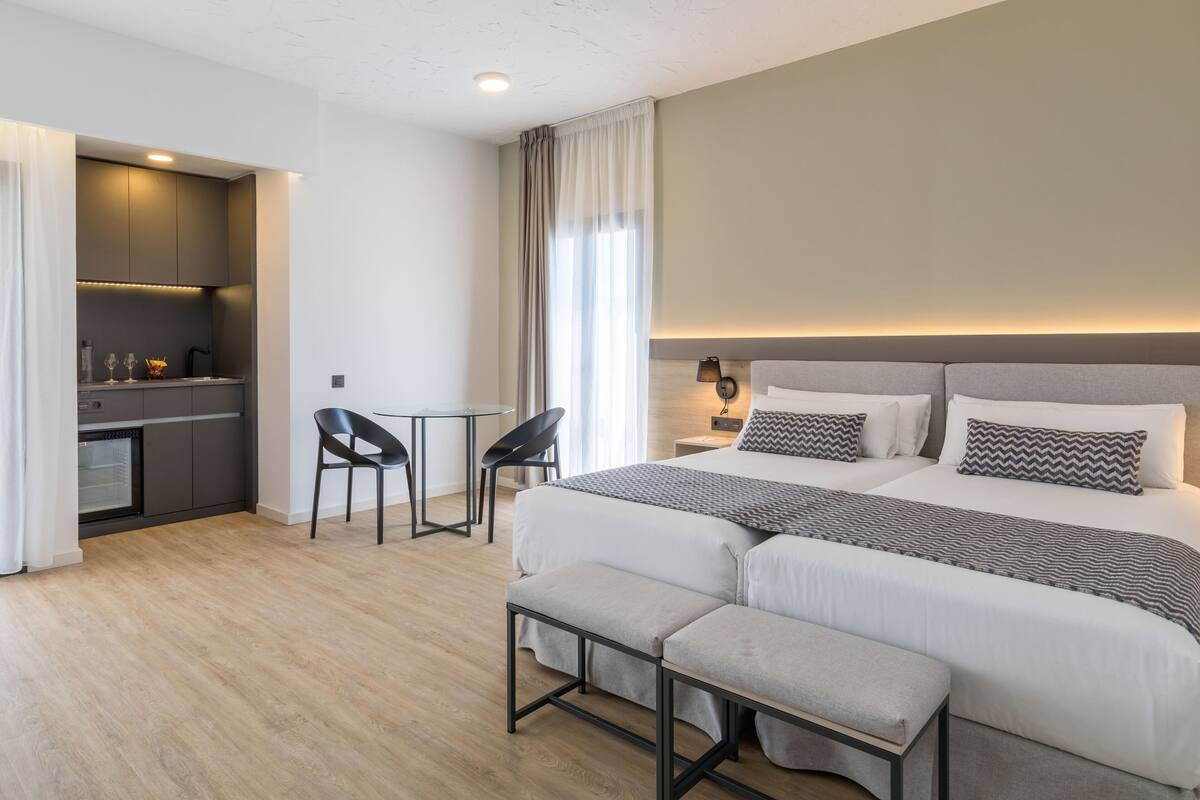 Una habitación de hotel moderna con una cama grande, un escritorio pequeño y una kitchenette.