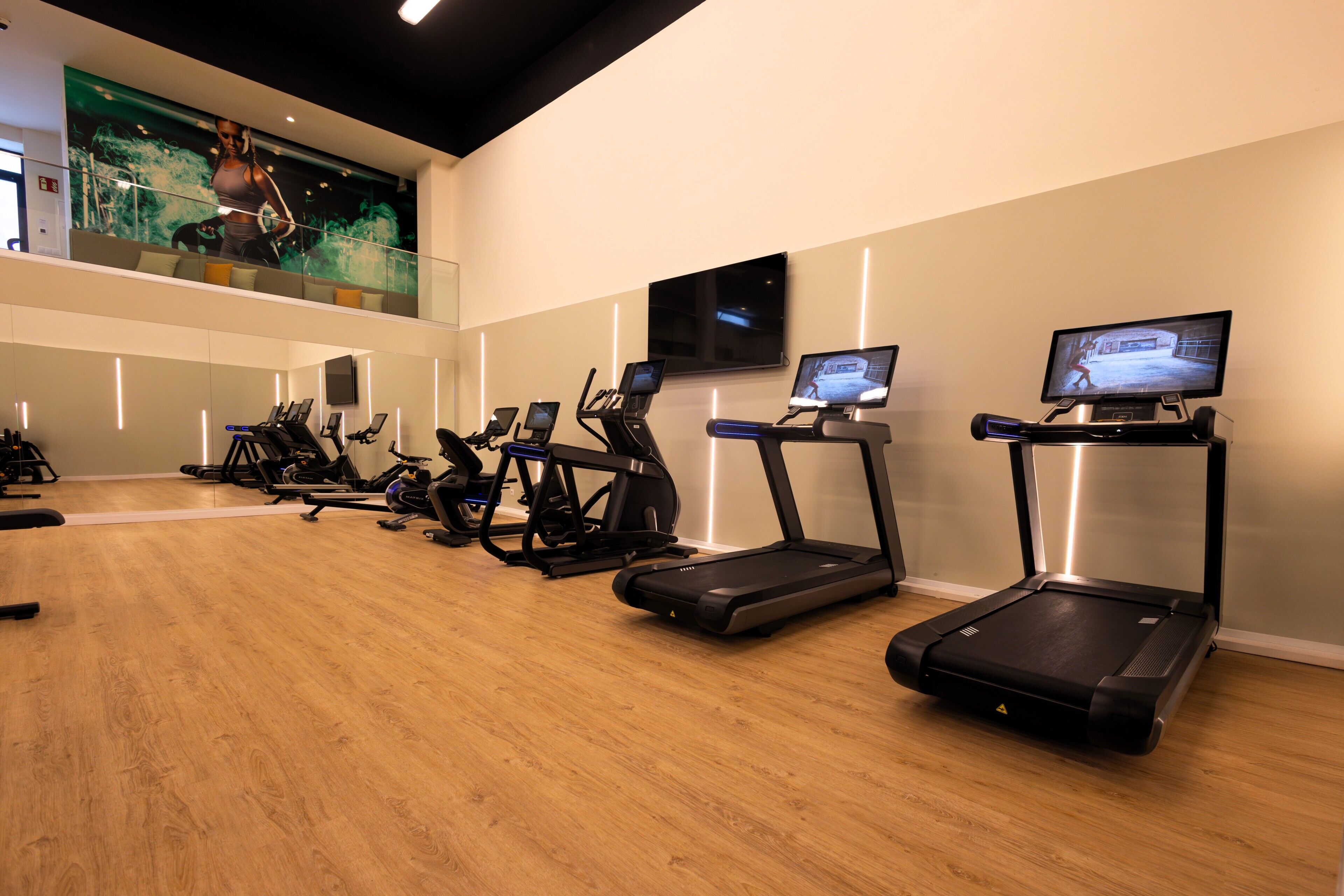 A fitness center with treadmills, stationary bikes, and a large screen displaying an image.