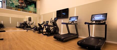 A fitness center with treadmills, stationary bikes, and a large screen displaying an image.
