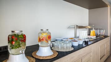 A breakfast bar with a fruit-infused water dispenser, a juice dispenser, and various breakfast items.