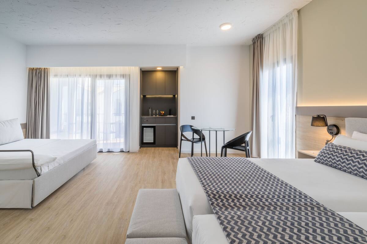 Una habitación de hotel con cama, sofá, escritorio y kitchenette.