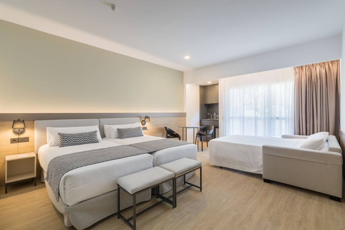 Una habitación de hotel moderna con una cama grande, un sofá, un escritorio y una silla.