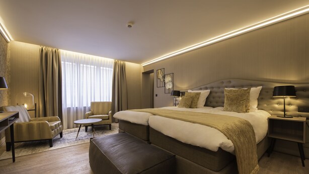 A modern hotel room with a large bed, a desk, a chair, and a small table. - Hotel Acacia (Bruges)