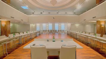 Un salón de conferencias con una larga mesa, sillas y una pantalla para proyector.
