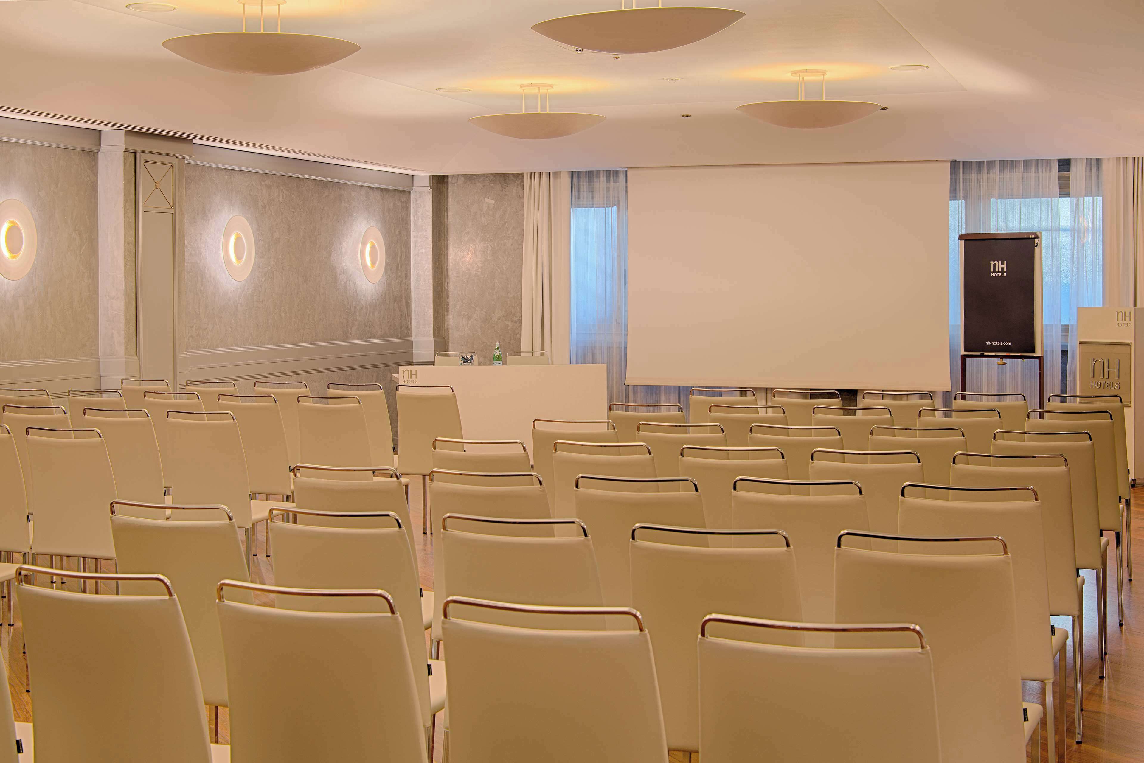 A conference room with rows of chairs, a podium, and a projection screen.