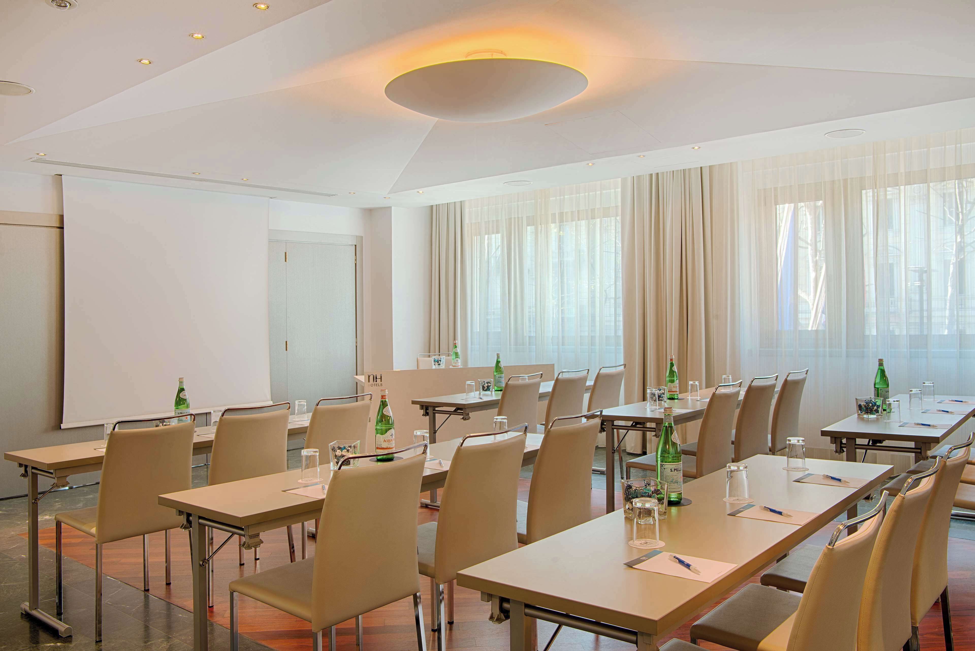 A conference room with tables, chairs, and a projector screen.