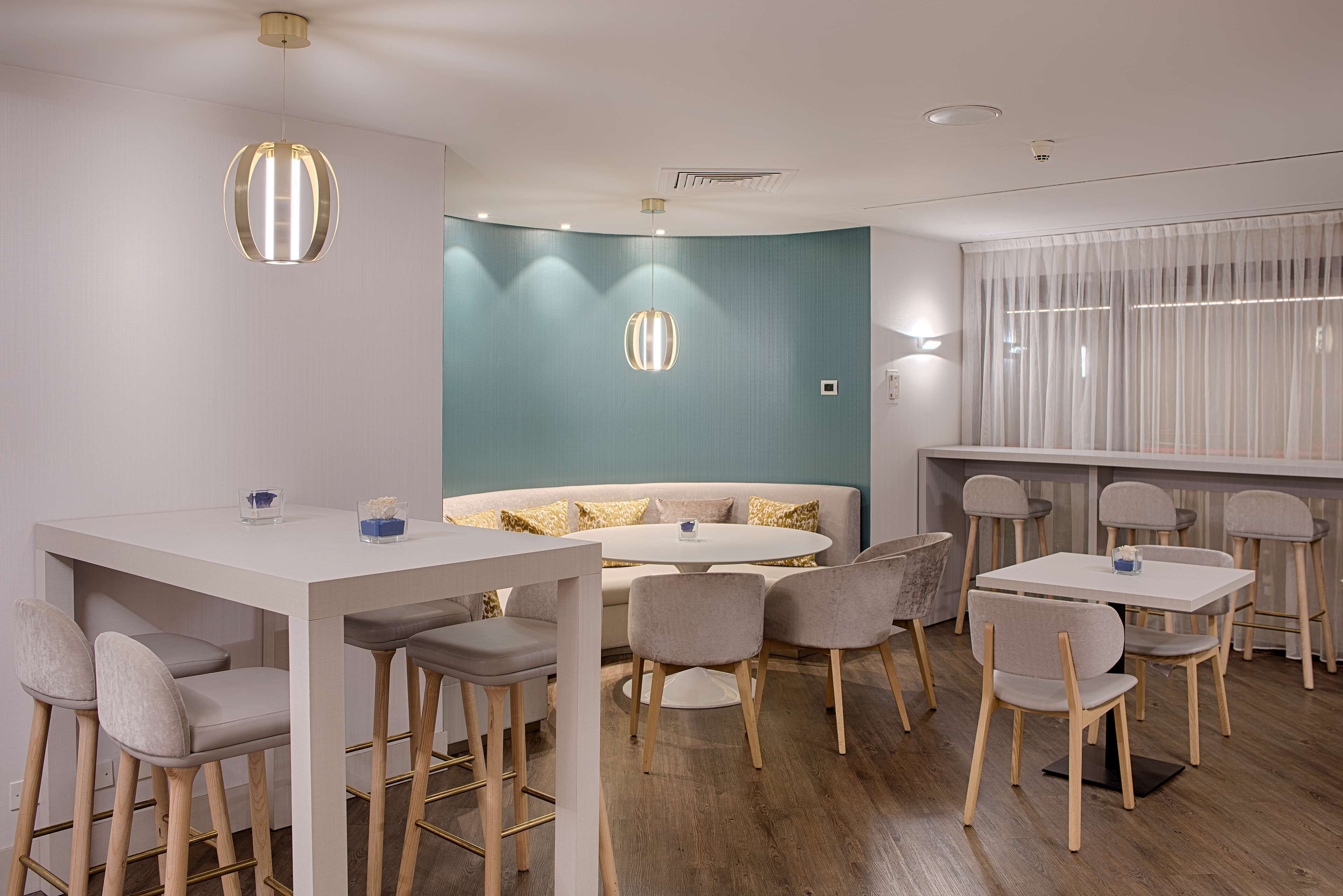 A modern dining area with a white table, grey chairs, and a blue accent wall.