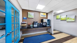 A reception area with a blue door, a Daybreak Breakfast sign, a coffee machine, and a fruit bowl. - Days Inn by Wyndham Fredericksburg North (Fredericksburg)