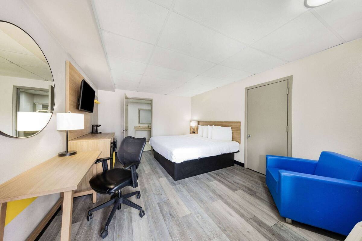 Ein Hotelzimmer mit Bett, Schreibtisch, Stuhl und einem blauen Sofa.