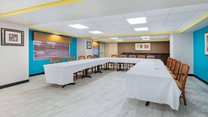 A conference room with a long table, chairs, and a projector screen. - Days Inn by Wyndham Fredericksburg North (Fredericksburg)
