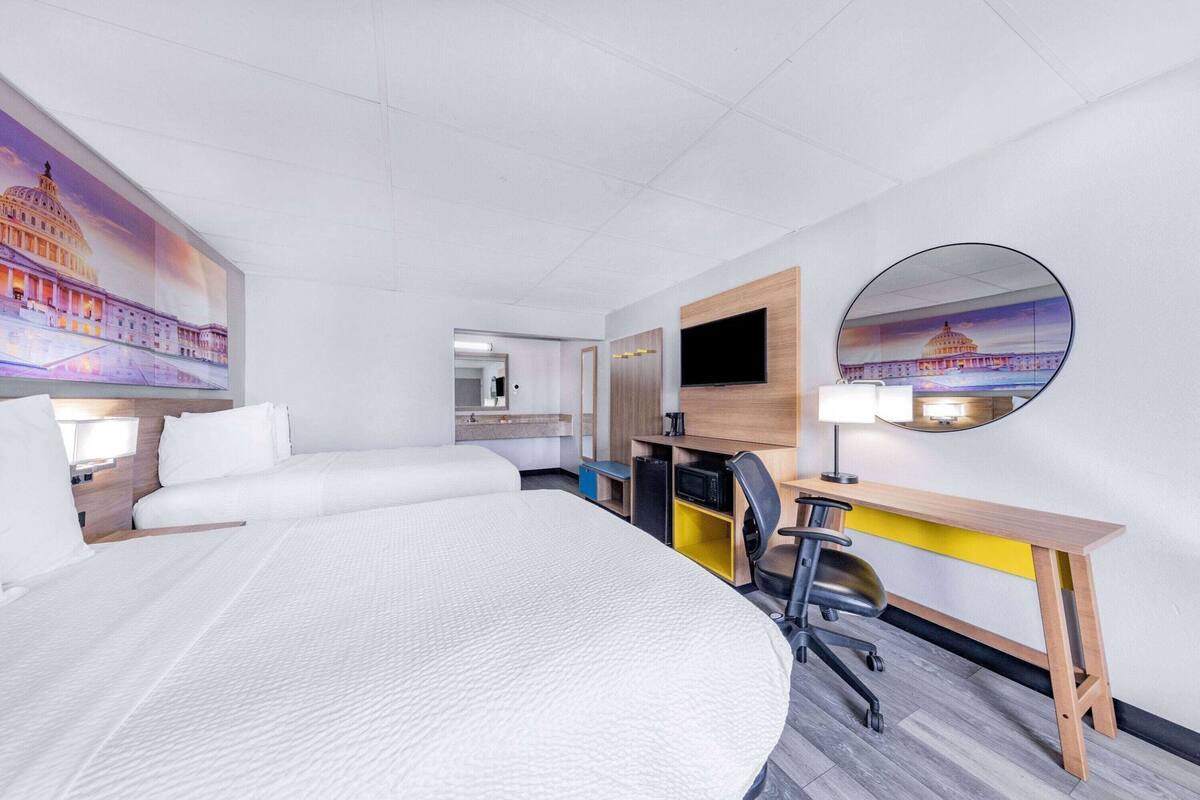 Ein Hotelzimmer mit einem großen Bett, einem Schreibtisch mit Stuhl, einem Fernseher und einem Spiegel.