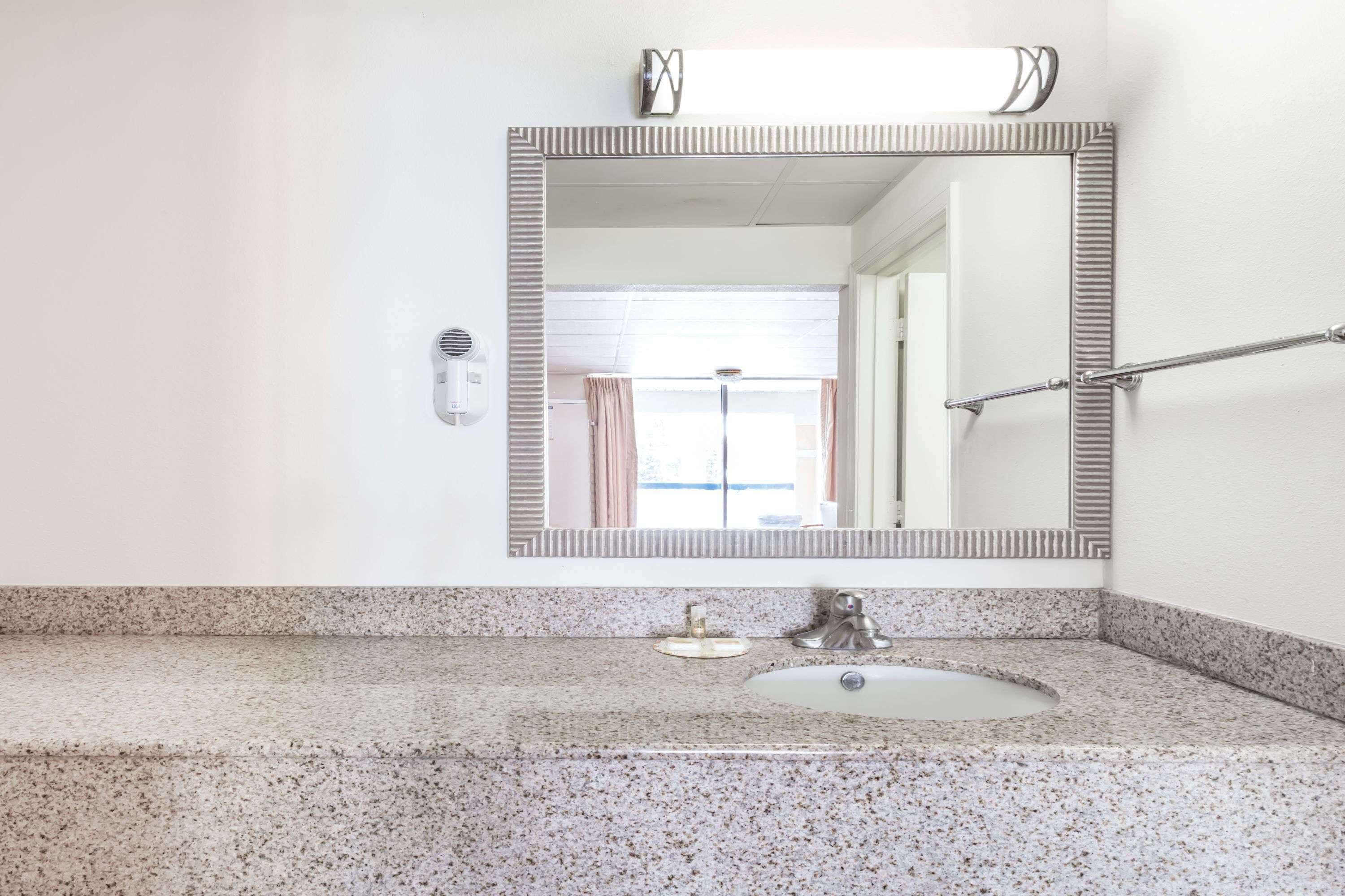 Un bagno con lavabo in granito, un lavandino, uno specchio e un portasciugamani.