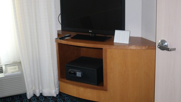 Ein Hotelzimmer mit einem Fernseher auf einem Holzboden, einer Fernbedienung und einem kleinen schwarzen Gerät auf dem Boden.