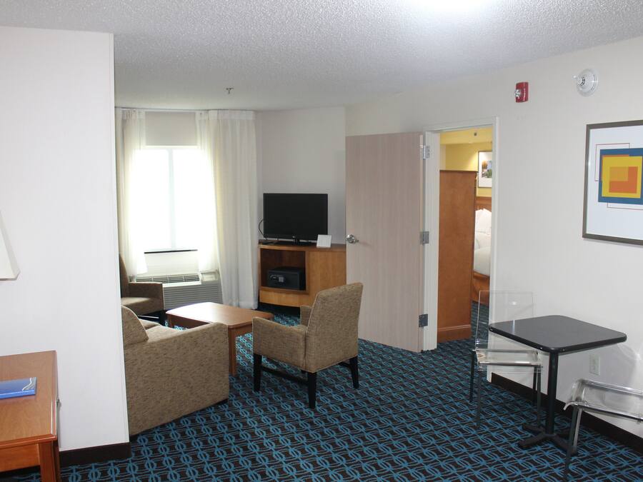 Una habitación de hotel con televisión, sofá, una mesita y escritorio.