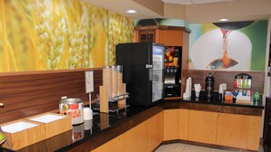 Un hall d’hôtel avec un réfrigérateur noir, un distributeur de boissons Pepsi et une machine à café.